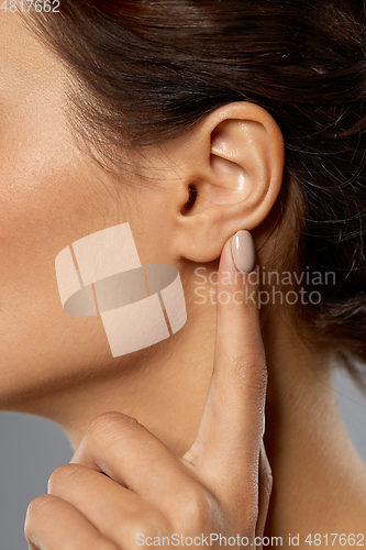 Image of close up of young woman pointing finger to her ear