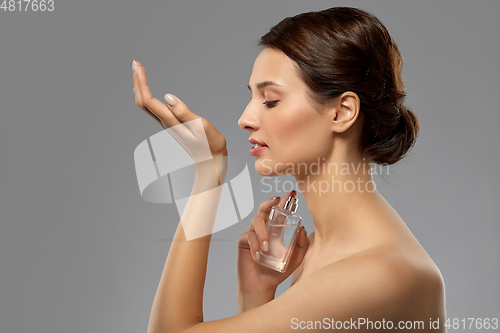 Image of happy woman smelling perfume from her wrist