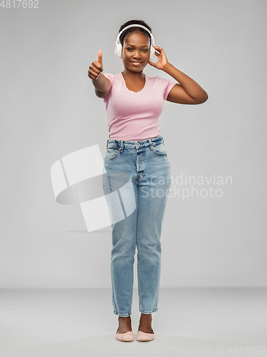 Image of african woman in headphones showing thumbs up