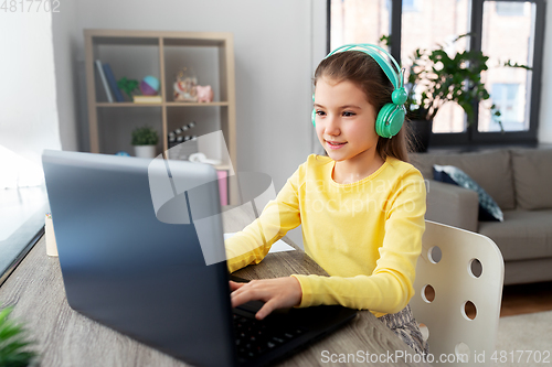 Image of girl in headphones with laptop computer at home