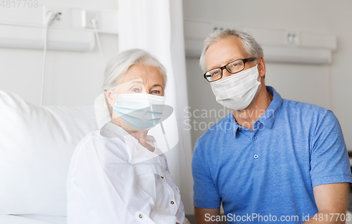 Image of senior couple in face masks meeting at hospital