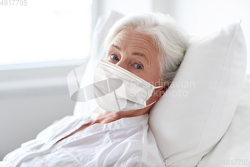 Image of old woman patient in mask lying in bed at hospital