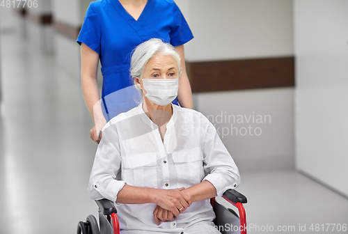 Image of senior woman in mask in wheelchair at hospital