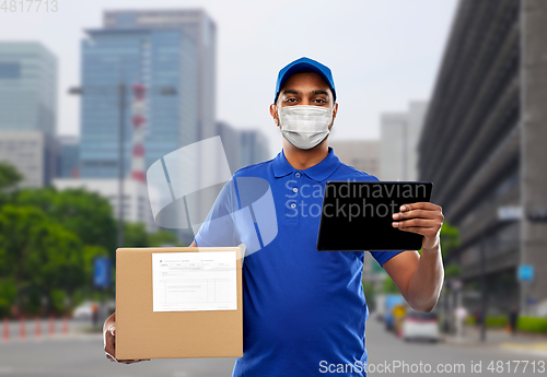 Image of delivery man in mask with tablet pc and parcel box