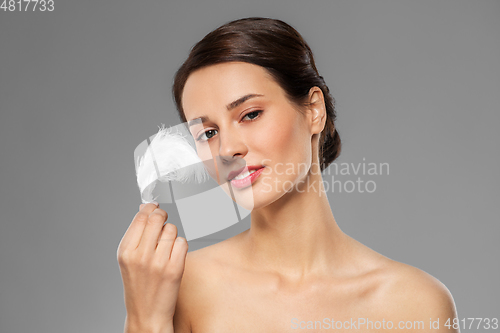 Image of beautiful woman with feather touching her face