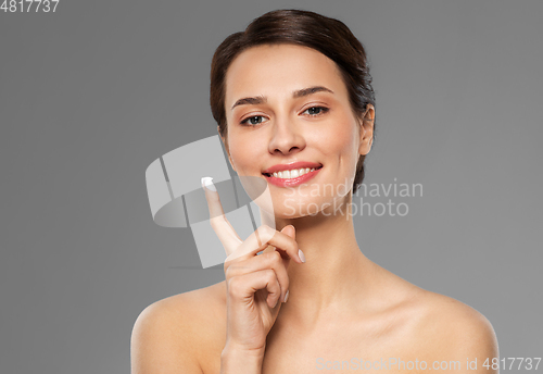 Image of young woman with moisturizing cream on finger