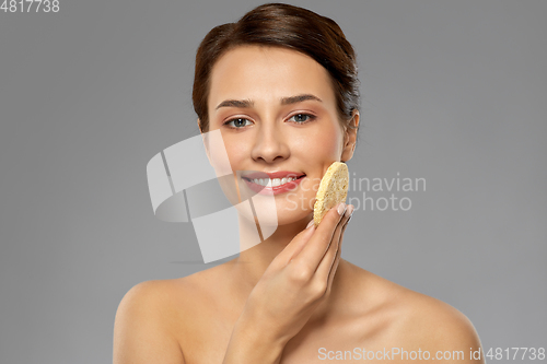 Image of young woman cleaning face with exfoliating sponge