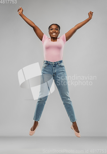 Image of happy african american woman jumping over grey