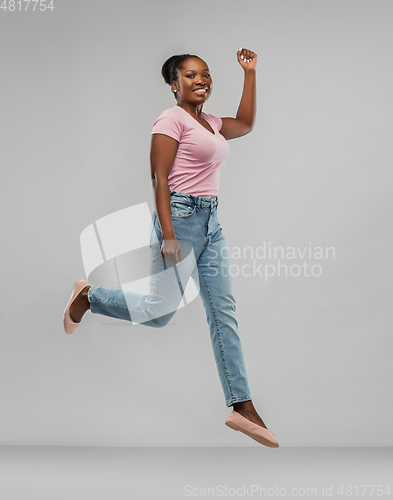 Image of happy african american woman jumping over grey
