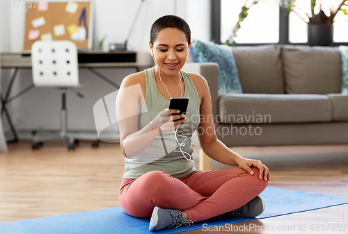Image of woman with earphones and smartphone doing sports