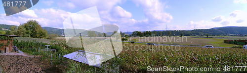 Image of Panoramic landscape: road, cars, fields, trees, sky with clouds, horizon