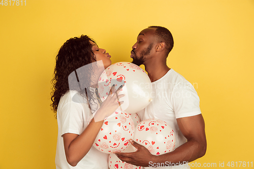 Image of Valentine\'s day celebration, happy african-american couple isolated on yellow background