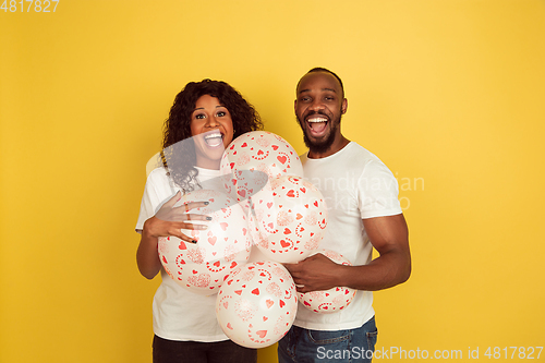 Image of Valentine\'s day celebration, happy african-american couple isolated on yellow background