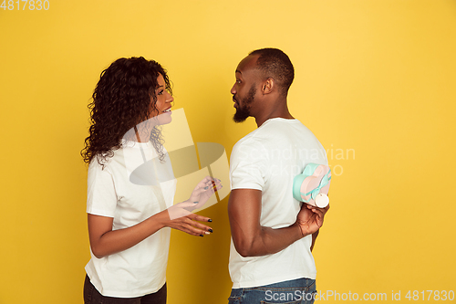 Image of Valentine\'s day celebration, happy african-american couple isolated on yellow background