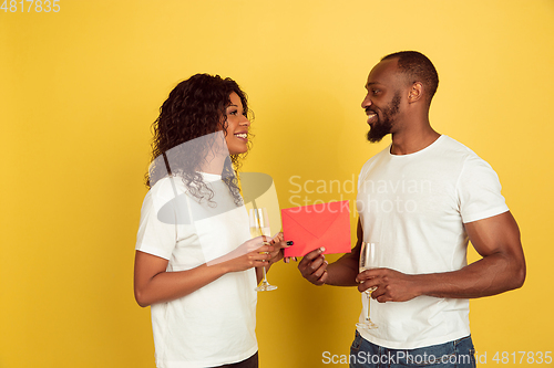 Image of Valentine\'s day celebration, happy african-american couple isolated on yellow background