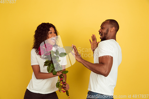 Image of Valentine\'s day celebration, happy african-american couple isolated on yellow background