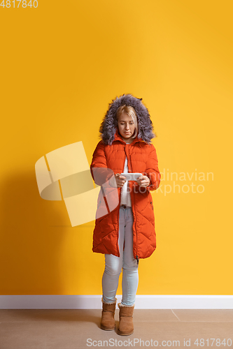 Image of Young caucasian woman using smartphone. Full body length portrait isolated over yellow background.