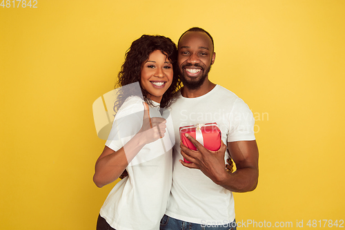 Image of Valentine\'s day celebration, happy african-american couple isolated on yellow background