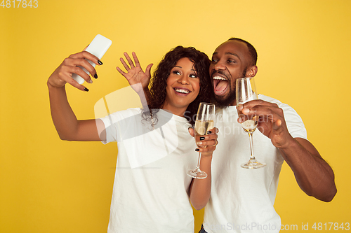 Image of Valentine\'s day celebration, happy african-american couple isolated on yellow background