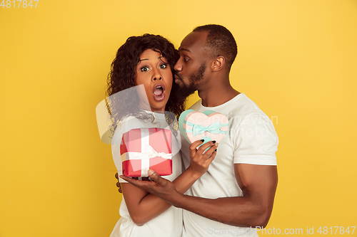 Image of Valentine\'s day celebration, happy african-american couple isolated on yellow background