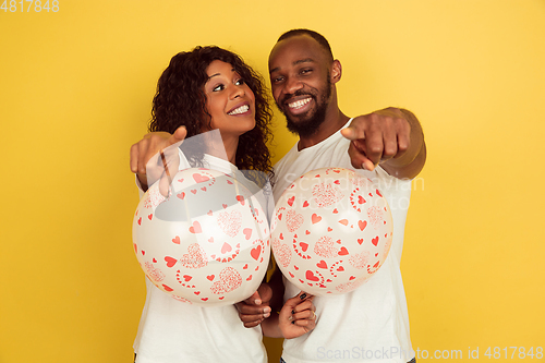 Image of Valentine\'s day celebration, happy african-american couple isolated on yellow background