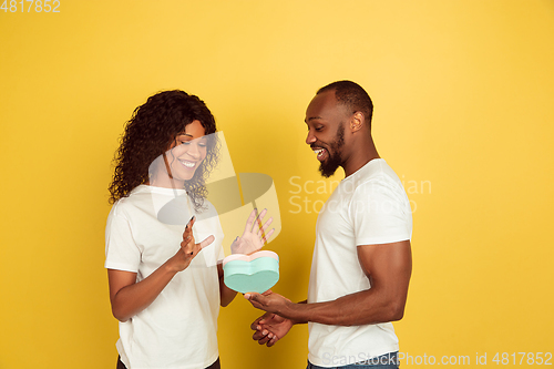 Image of Valentine\'s day celebration, happy african-american couple isolated on yellow background