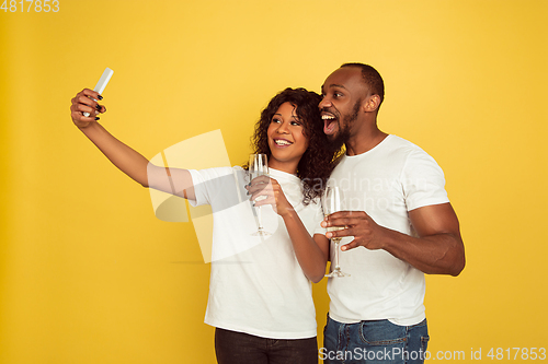 Image of Valentine\'s day celebration, happy african-american couple isolated on yellow background