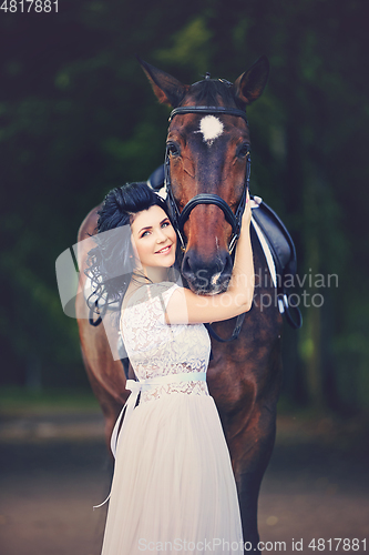 Image of beautiful girl in dress with horse