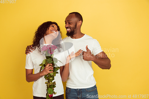 Image of Valentine\'s day celebration, happy african-american couple isolated on yellow background