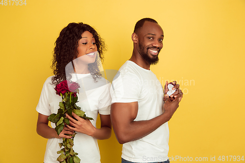 Image of Valentine\'s day celebration, happy african-american couple isolated on yellow background