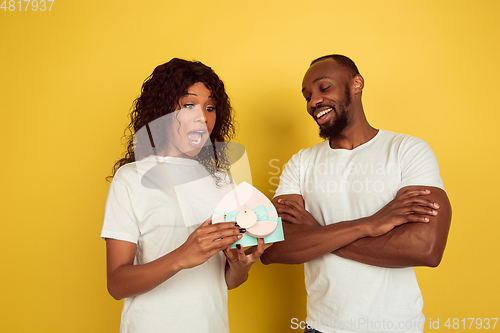 Image of Valentine\'s day celebration, happy african-american couple isolated on yellow background