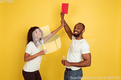 Image of Valentine\'s day celebration, happy african-american couple isolated on yellow background