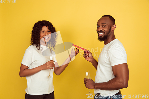 Image of Valentine\'s day celebration, happy african-american couple isolated on yellow background