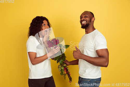 Image of Valentine\'s day celebration, happy african-american couple isolated on yellow background