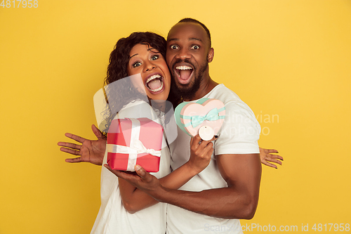 Image of Valentine\'s day celebration, happy african-american couple isolated on yellow background