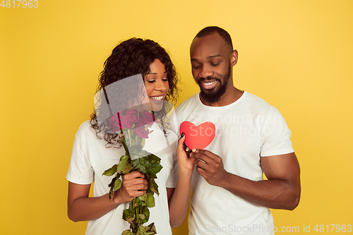 Image of Valentine\'s day celebration, happy african-american couple isolated on yellow background