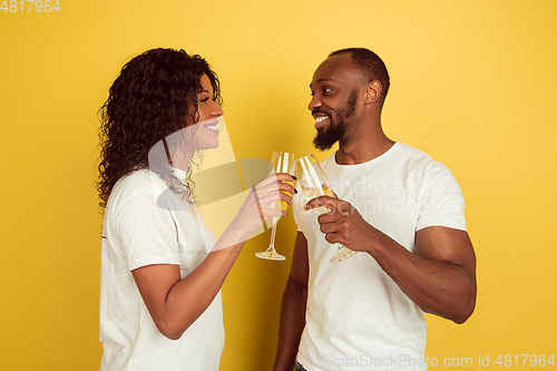 Image of Valentine\'s day celebration, happy african-american couple isolated on yellow background