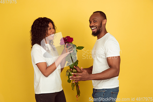 Image of Valentine\'s day celebration, happy african-american couple isolated on yellow background