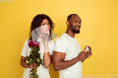 Image of Valentine\'s day celebration, happy african-american couple isolated on yellow background