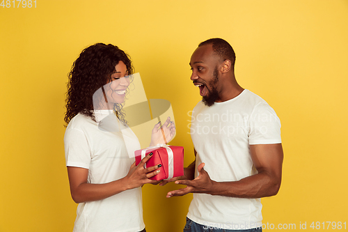 Image of Valentine\'s day celebration, happy african-american couple isolated on yellow background