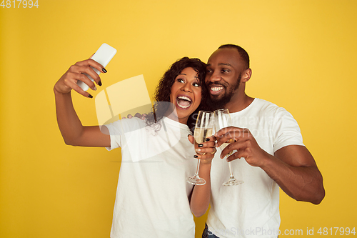 Image of Valentine\'s day celebration, happy african-american couple isolated on yellow background