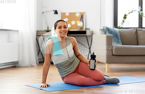 Image of woman with bottle and towel after sports at home