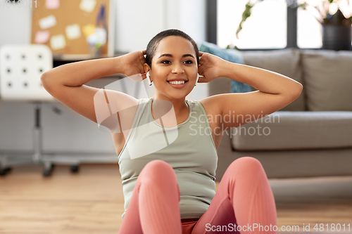 Image of african woman doing abdominal exercises at home