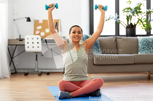 Image of african woman with dumbbells exercising at home