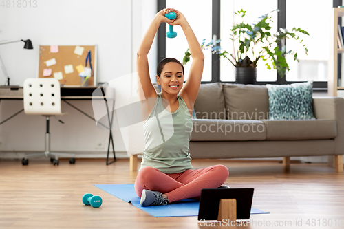 Image of woman with tablet pc and dumbbell training at home