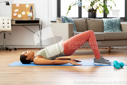 Image of woman doing pelvic lift abdominal exercise at home