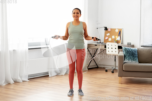 Image of african woman exercising with jump rope at home