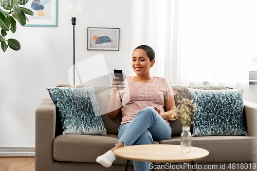 Image of african american woman with smartphone at home