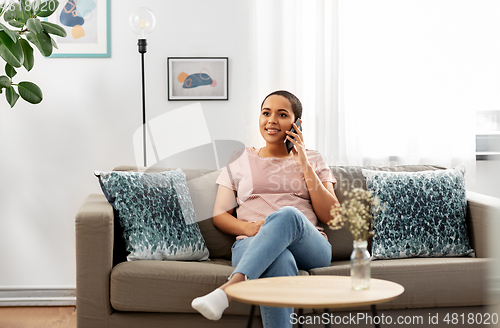 Image of african woman calling on smartphone at home