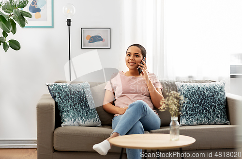 Image of african woman calling on smartphone at home